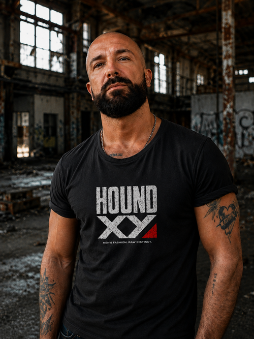 Man wearing the HOUND XY Raw Instinct graphic T-shirt in an abandoned industrial warehouse.